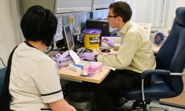 Female patient and male doctor at computer screen in consulting room