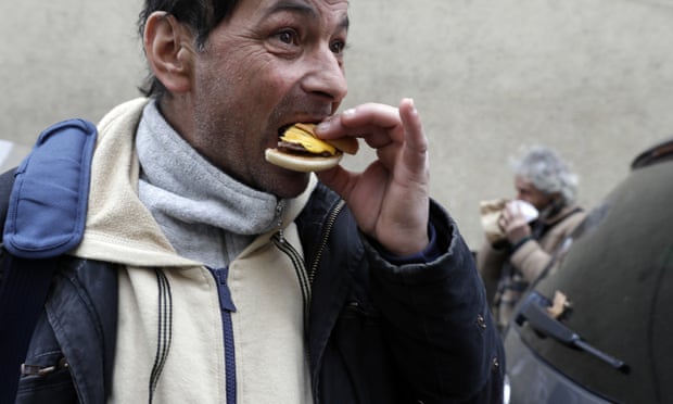 Homeless people eat hamburgers outside a Medicina Solidale centre in Rome