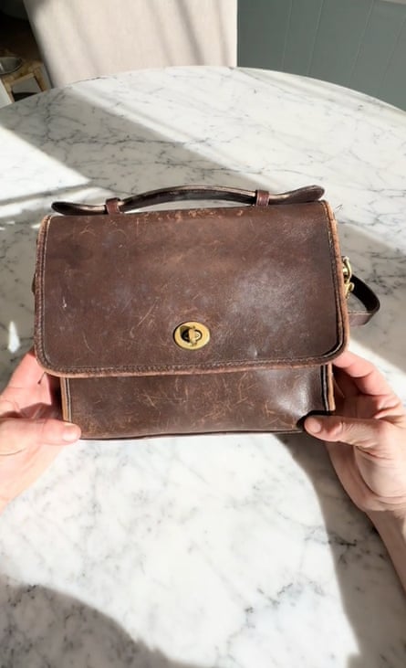 Hands holding a scuffed, vintage handbag