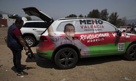 A bodyguard of Institutional Revolutionary Party, PRI, mayoral candidate Guillermo Valencia, takes his assault rifle from the back of the armoured SUV they travel in, during one of Valencia’s campaign stops in Morelia, Michoacan state.