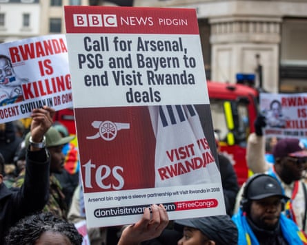 Protestors outside Broadcasting House in London hold up signs protesting football teams taking sponsorship money from Rwanda