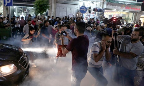 Palestinian protesters run after special police fired teargas during the protest in Ramallah on Wednesday.