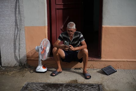 Man charges his phone using a small portable solar panel