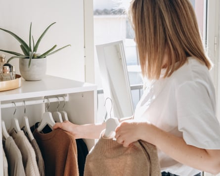 A young woman choosing a cashmere sweater in her bedroom