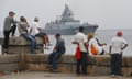 People watch a ship belonging to the Russian Navy flotilla