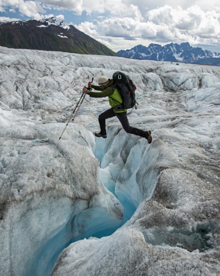A climber jumps over a glacial stream on the Ruth Glacier in Denali national park.