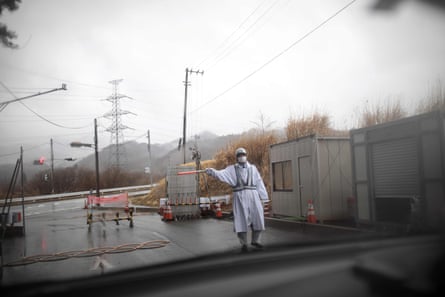 A guard gesturing at a checkpost exit from the exclusion zone of Futaba town, Fukushima prefecture.