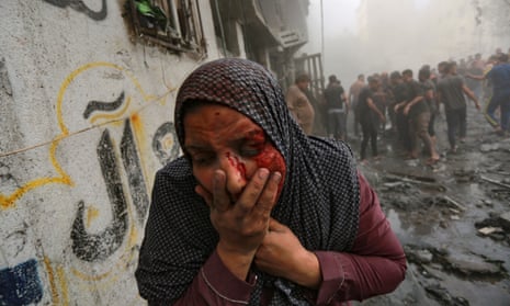 A wounded Palestinian woman runs away following Israeli airstrikes on Gaza City on 23 October.