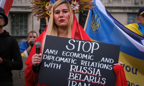 A protester in London holds up a sign asking to stop economic and diplomatic relations with Russia, Belarus and Iran.