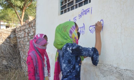 Writing slogans demanding free education for all girls until at least grade 12 on the walls in a Karauli village.