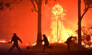 Fire officers and volunteer firefighters try to beat back blazes encroaching on properties near Termeil, south of Sydney.
