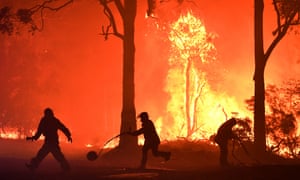 RFS volunteers and NSW Fire and Rescue officers fight a bushfire encroaching on properties between Batemans Bay and Ulladulla