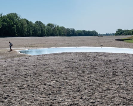 A man walks across a dry riverbed