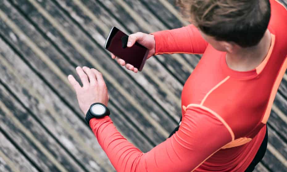 A runner checks his sport performance on his mobile phone and smartwatch
