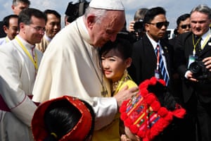 The pope is greeted by children in traditional clothing upon his arrival at Yangon international airport on 27 November