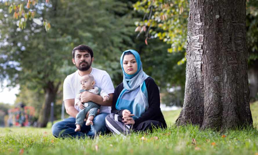 Firas (not his real name), a former guard at the British embassy in Kabul, sitting on the grass under a tree with his wife and son