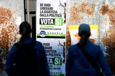 People walk past campaign posters to promote the Yes vote to the referendum on Justice reform