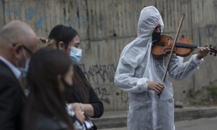 The violinist Antonio Hernández plays for the relatives of a Covid-19 victim at Serafin Cemetery in Bogota last week.