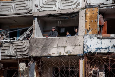 A family examines the destruction at their apartment building where an intercepted Russian rocket hit in Kyiv