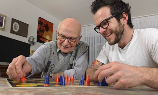 Two men, one elderly and one younger, playing board game together