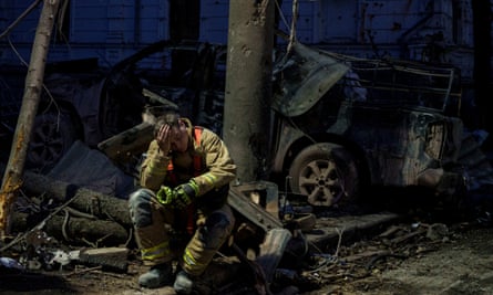 A rescue worker sits resting next to wreckage of a university building