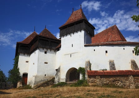 Fortified church in Viscri, Transylvania region, Romania, with white walls and red-tiled turrets