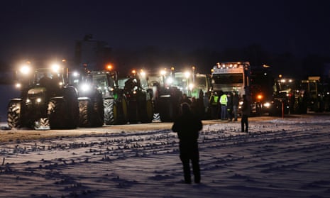 People stand beside tractors, as German farmers take part in a protest in Taufkirchen near Munich