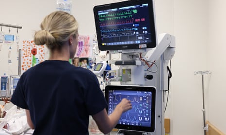 An intensive care nurse monitors a computer screen showing a patient's health data