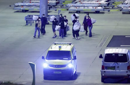 People wearing protective face masks carry belongings.