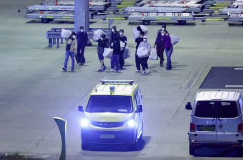 People wearing protective face masks carry belongings.