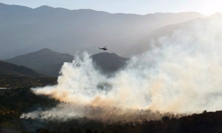 A helicopter releases water on to a wildfire in Rethimno, Greece, that was rekindled by strong winds.