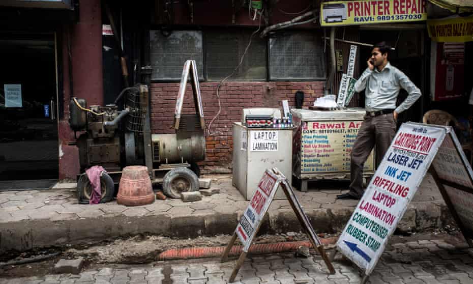 A shopkeeper stands next to a generator outside a commercial complex in Nehru Place, New Delhi