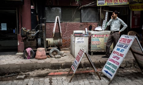 A shopkeeper stands next to a generator outside a commercial complex in Nehru Place, New Delhi, India.