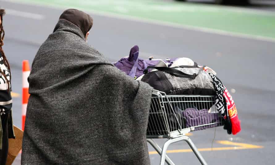 A homeless person pushes a trolley.