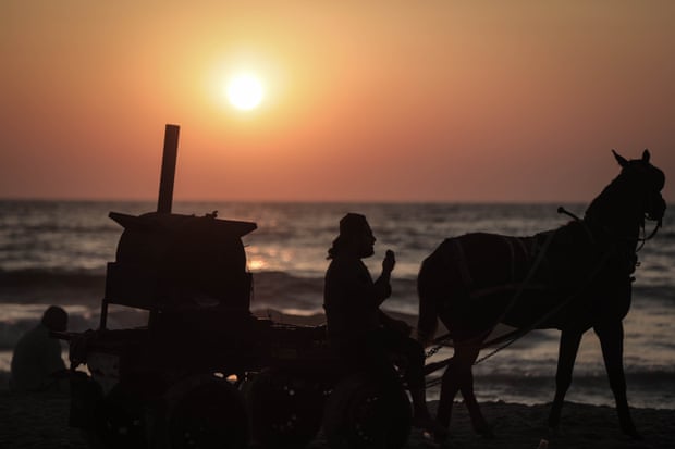 A sweet potato seller who sells produce on horseback returns to a fixed spot on the beach.