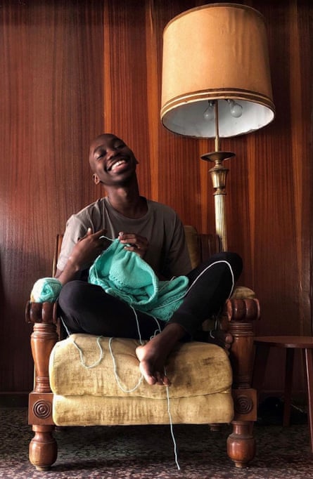 Ola Ogunlolu sitting on a chair, knitting