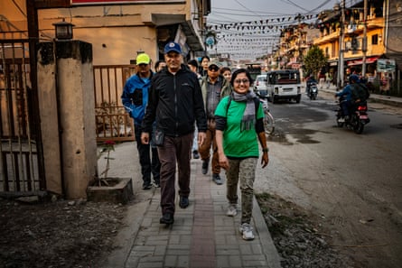 A woman and a man walk down the street towards us. Other people walk behind them
