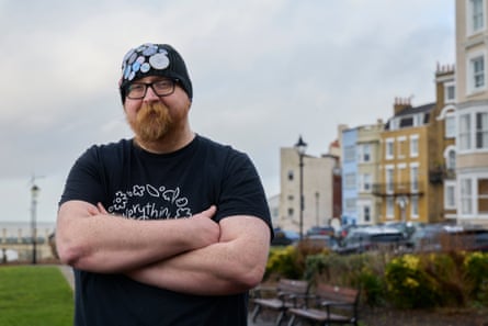 Man in a black T-shirt and black beanie hat stood outside