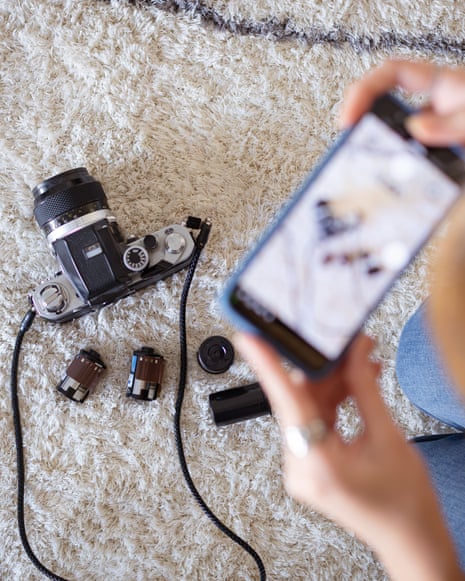 Person capturing vintage film camera with smartphone