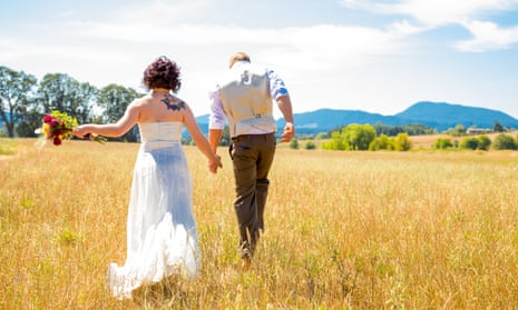 Bride and groom walking together on their wedding day through a field.