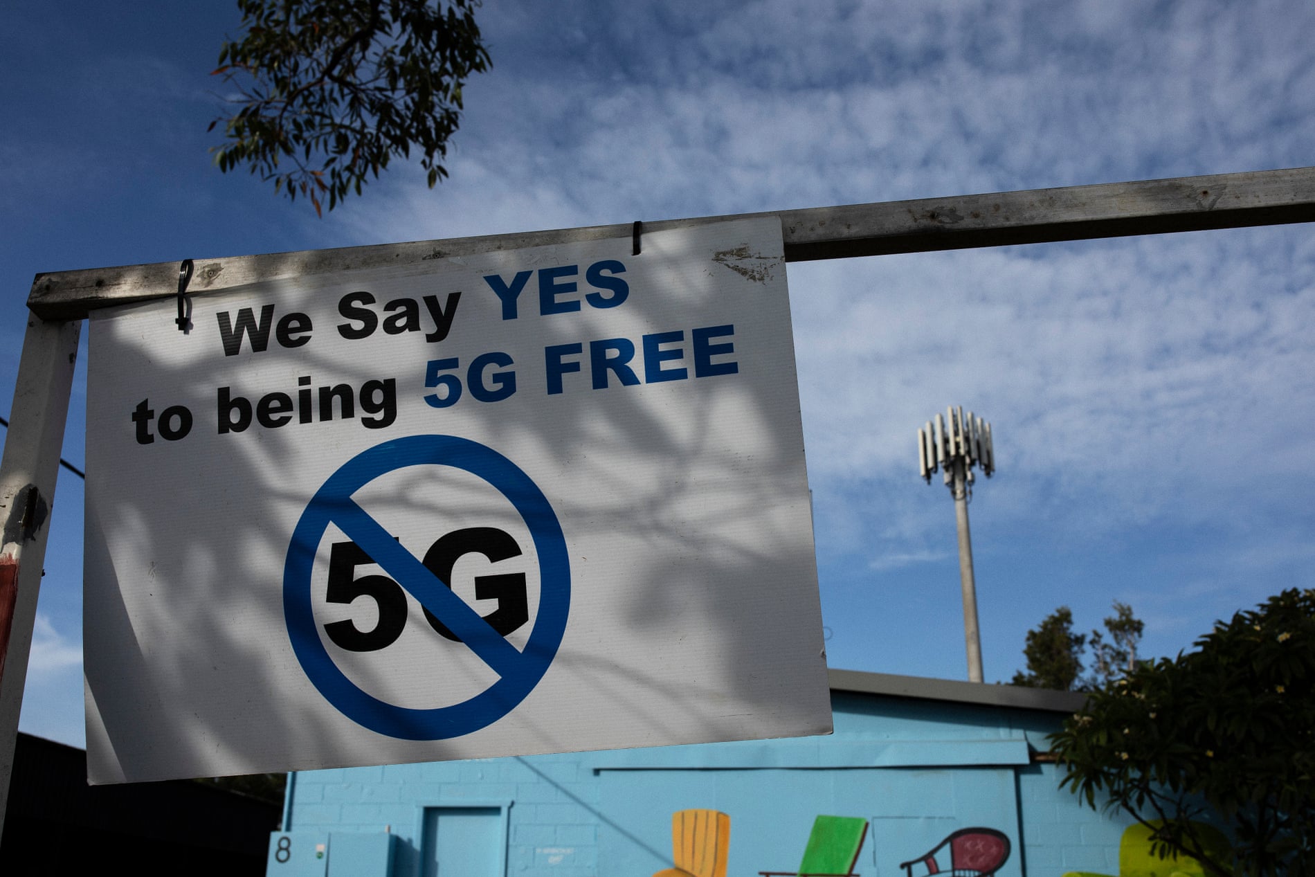Anti-5G signage at a Telstra exchange facility in Byron Bay with the Telstra transmission tower seen in the background. 