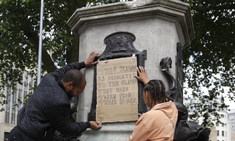 A banner is taped on the pedestal of the toppled Edward Colston statue.