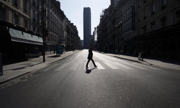 A woman crosses an empty street in Paris during the nationwide confinement.