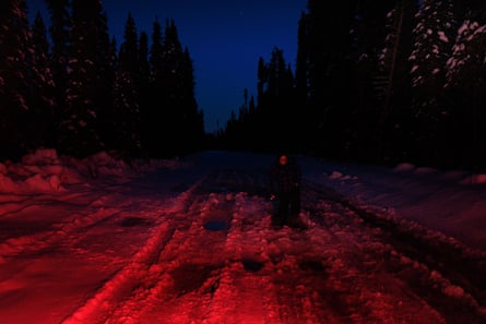 Rachel Wesley stands holding a torch in semi-darkness inspecting tracks in slushy snow.