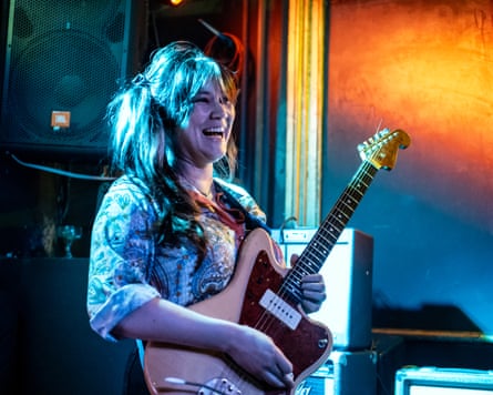 Wendy Eisenberg holding an electric guitar and grinning