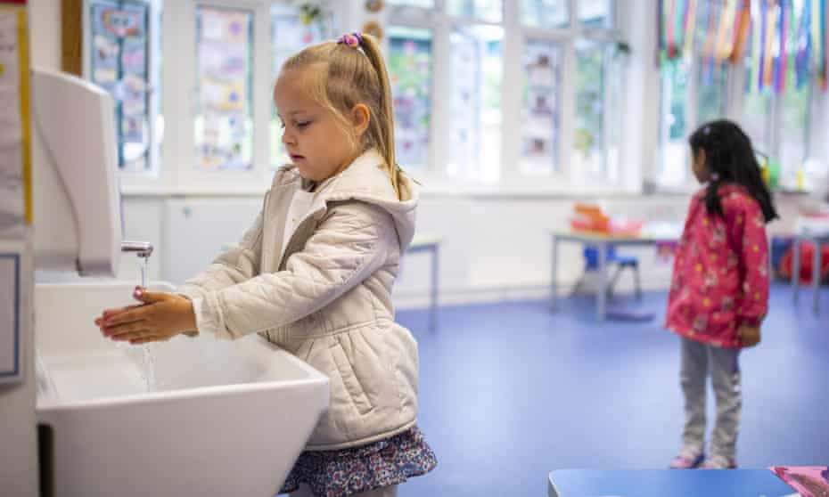 Socially distanced children washing hands in classroom