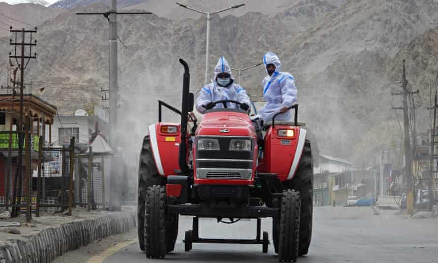 Health workers wearing protective gear ride a tractor as they sanitise a street with disinfectant amid the coronavirus pandemic in Leh, India.