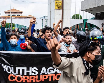 Young people shouting and raising their fists behind a ‘Youths against corruption’ banner