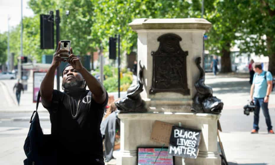 A man poses for a selfie at the site of the toppled statue of Edward Colston in Bristol