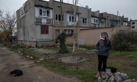 A girl in front of her battered apartment where she lives with her mother and sister 